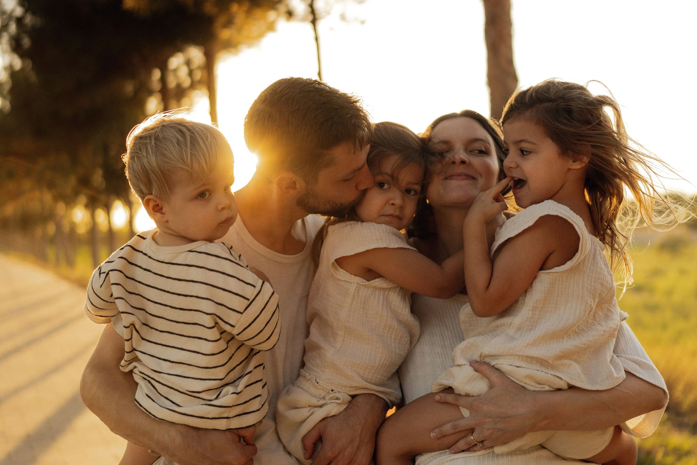 Parents holding their three young children in warm evening light