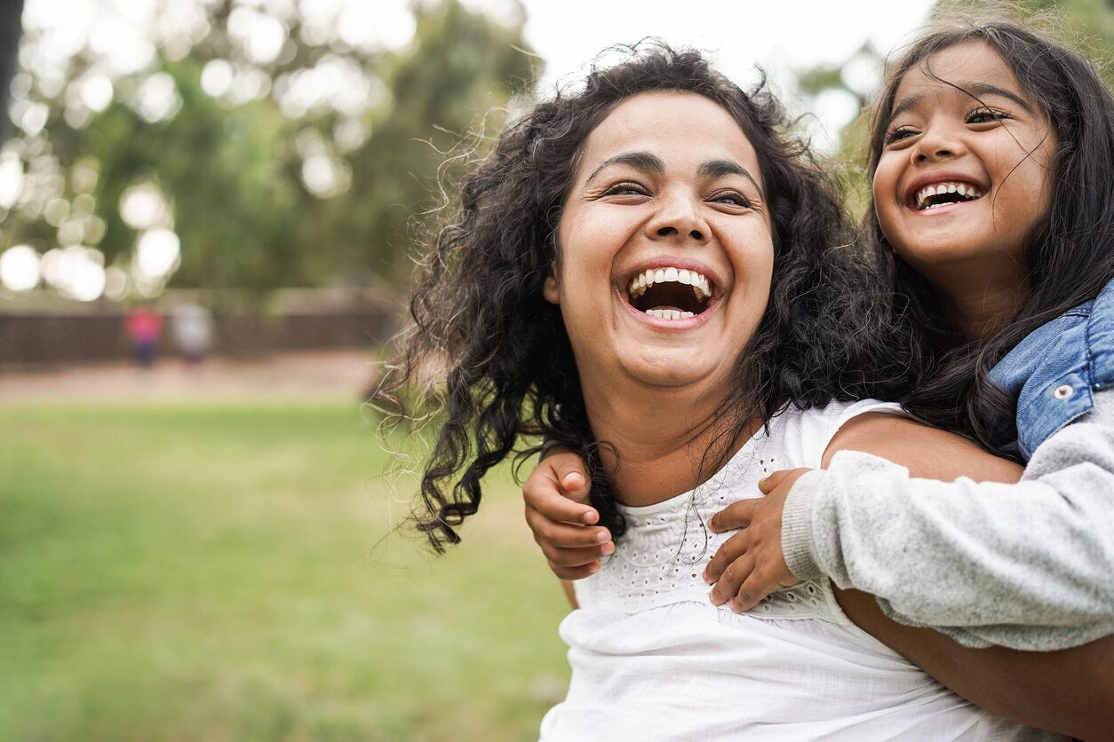 Woman and girl laughing together on a lawn