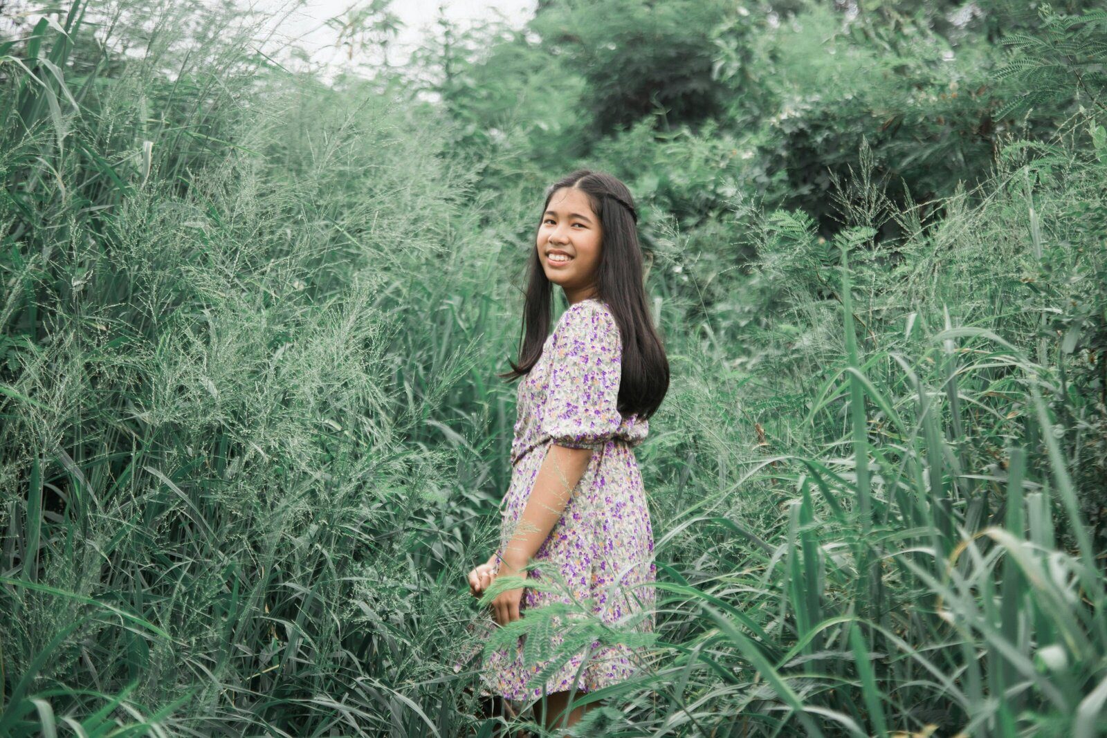 Teen standing among tall green grass